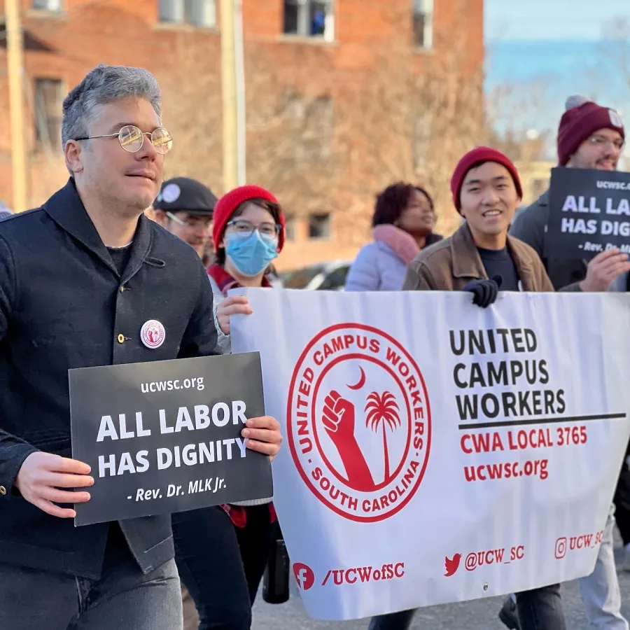 Union members march with sign that says "All labor has dignity" - Rev. Dr. MLK Jr. and banner that reads "United Campus Workers CWA Local 3765"