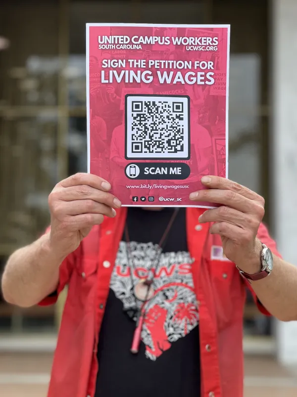 A union worker at USC holds up the petition for a living wage